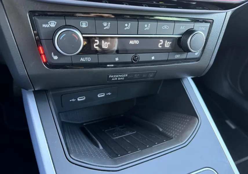 Gros plan sur la console centrale du SEAT Arona 2024, montrant la commande de climatisation et la station de recharge sans fil.