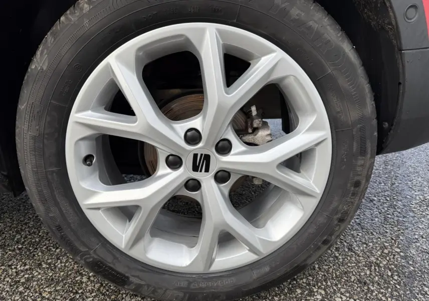Gros plan sur la roue avant droite d'une SEAT Arona rouge, mettant en valeur la jante alliage argentée au design moderne.