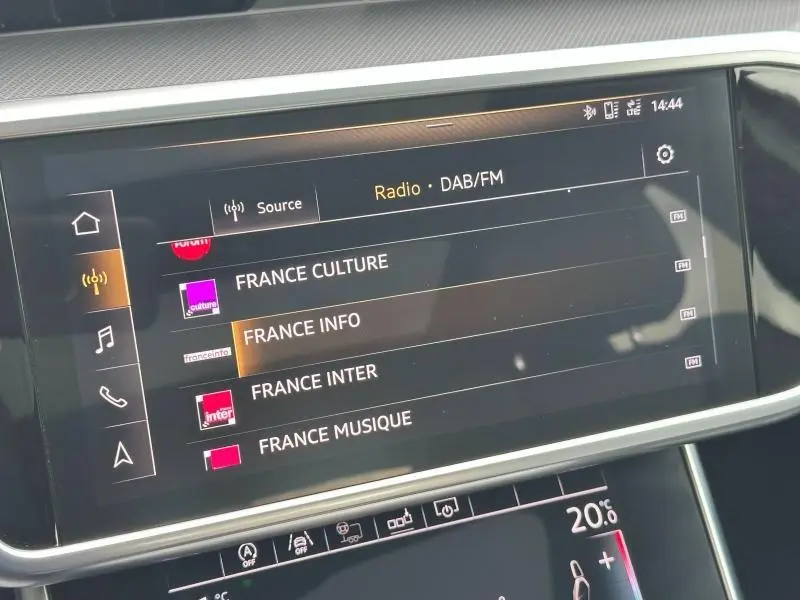 Écran tactile central de l'Audi A6 Avant noir métal affichant les stations radio DAB/FM en intérieur.