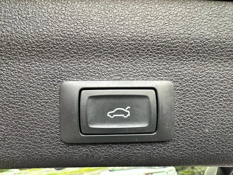 Bouton d'ouverture électrique du coffre sur un panneau intérieur noir texturé d'Audi A6 Avant noir métal