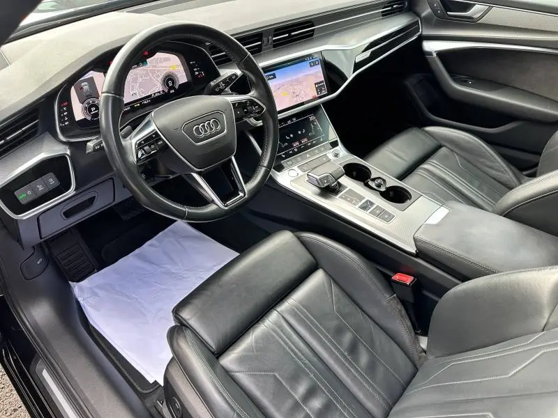 Vue intérieure côté conducteur de l'Audi A6 Avant 45 TDI noire, avec tableau de bord digital et sièges cuir noirs sportifs.