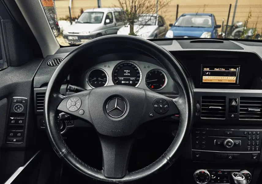 Vue intérieure centrée sur le volant cuir Mercedes GLK 220 CDI 2010 avec tableau de bord et écran multimédia.