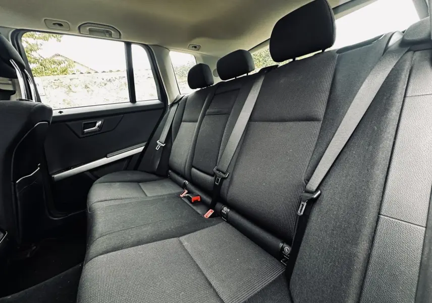 Vue latérale gauche de la banquette arrière noire du Mercedes GLK 220 CDI avec ceintures trois points et appuie-têtes.
