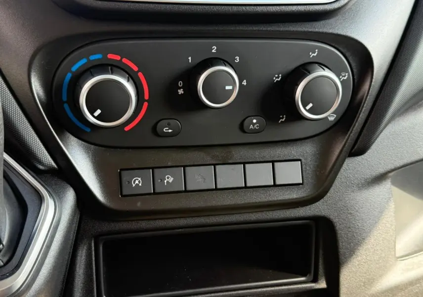 Gros plan sur les commandes de climatisation noires du tableau de bord de l'IVECO Daily blanc 2026.
