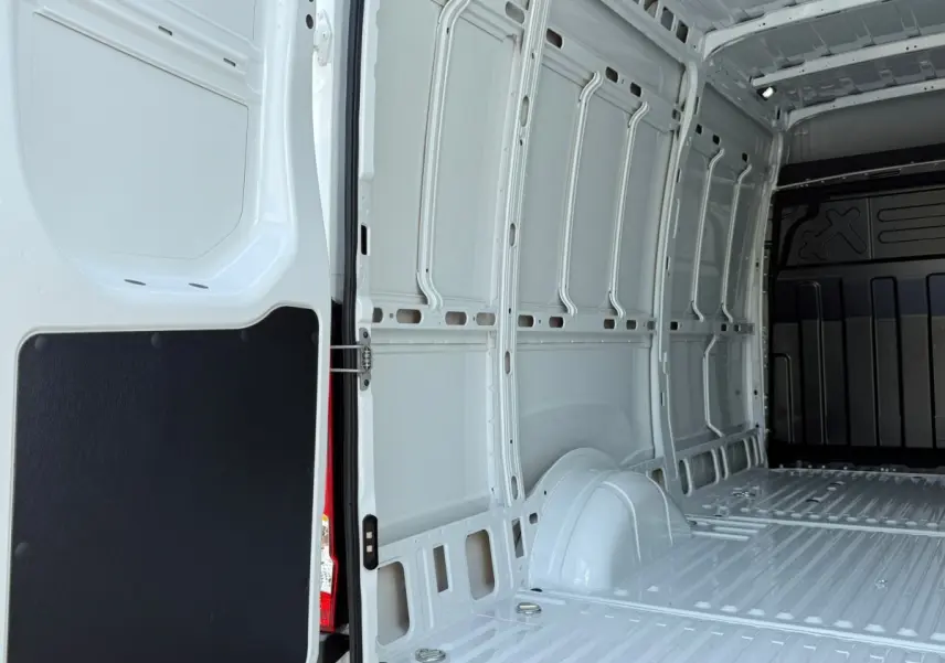 Vue intérieure arrière du fourgon Iveco Daily blanc 2026, montrant l’espace de chargement vide et les parois métalliques.