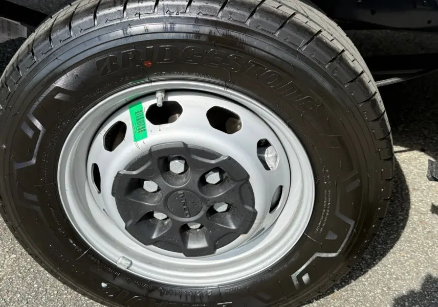 Gros plan sur la roue avant droite de l'IVECO Daily blanc, mettant en valeur la jante acier et le pneu Bridgestone.