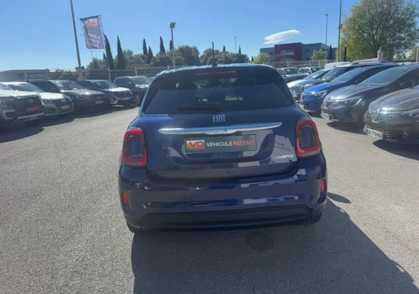 Vue arrière d'une Fiat 500X bleu foncé hybride 2024, avec feux arrière rouges et vitres teintées.