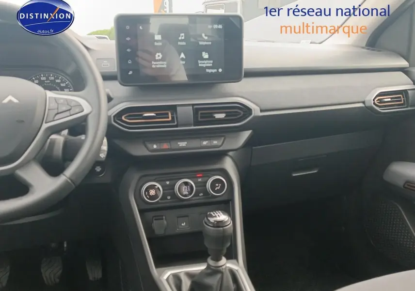 Intérieur de la Dacia Sandero 2025 vue de face, tableau de bord noir avec écran tactile et boîte manuelle.