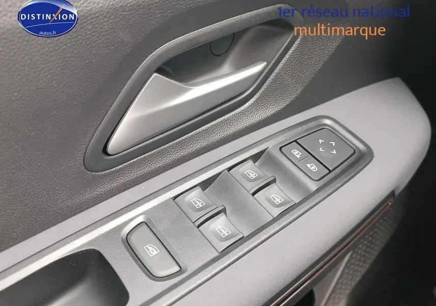 Gros plan sur la commande des vitres électriques et la poignée intérieure côté gauche d'une Dacia Sandero noire 2025.
