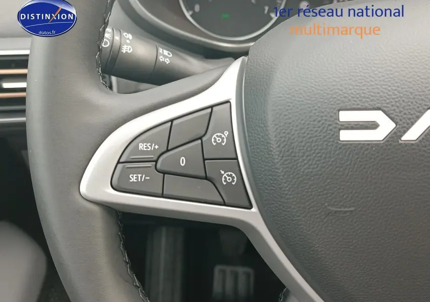 Gros plan sur la partie gauche du volant noir de la Dacia Sandero 2025 avec commandes de régulateur de vitesse intégrées.
