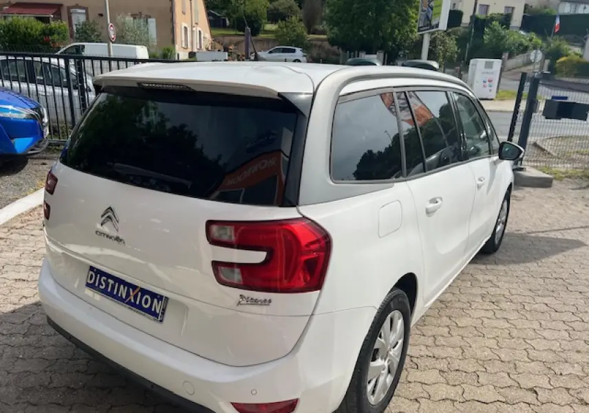 Vue 3/4 arrière droite d'un Citroën Grand C4 Picasso blanc avec vitres surteintées et jantes alliage 16 pouces.