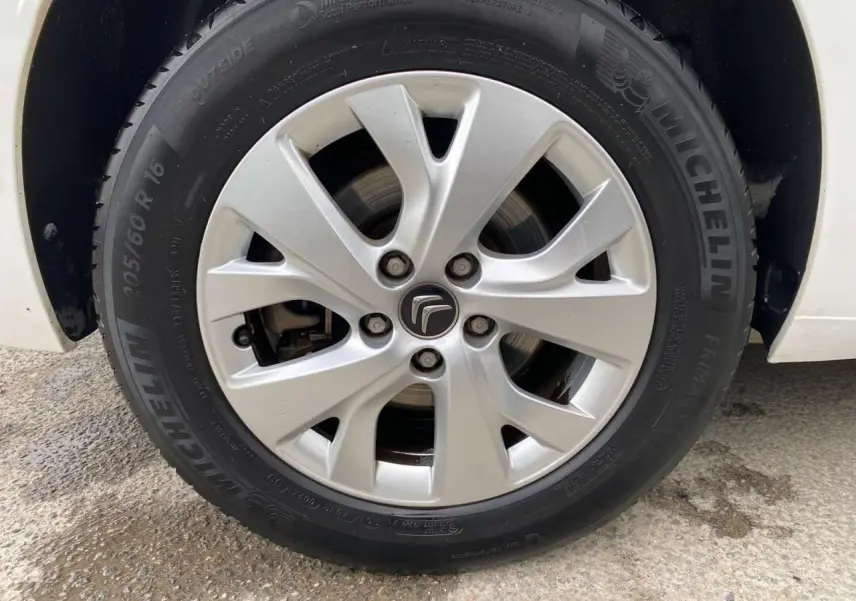 Gros plan sur la jante alliage 16 pouces Notos argentée du côté gauche d'un Citroën Grand C4 Picasso blanc.