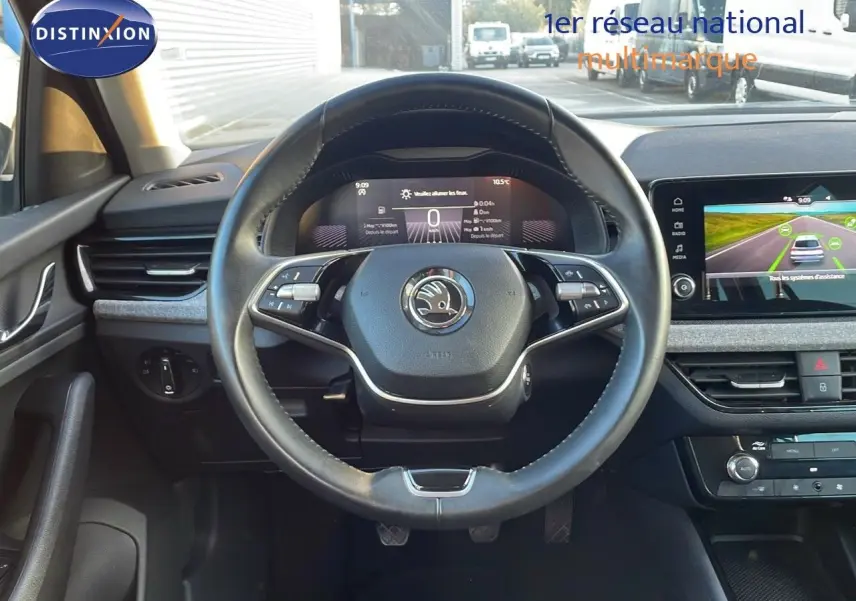 Vue intérieure centrée sur le volant cuir du Skoda Kamiq 2024 avec tableau de bord numérique et écran tactile.
