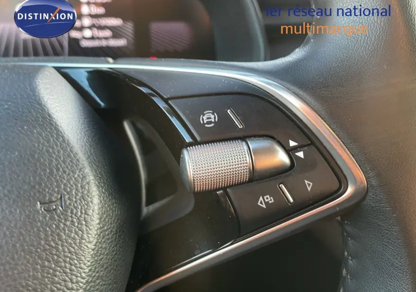 Gros plan sur les commandes du volant noir du Skoda Kamiq 2024, avec molette métallique et boutons multifonctions.