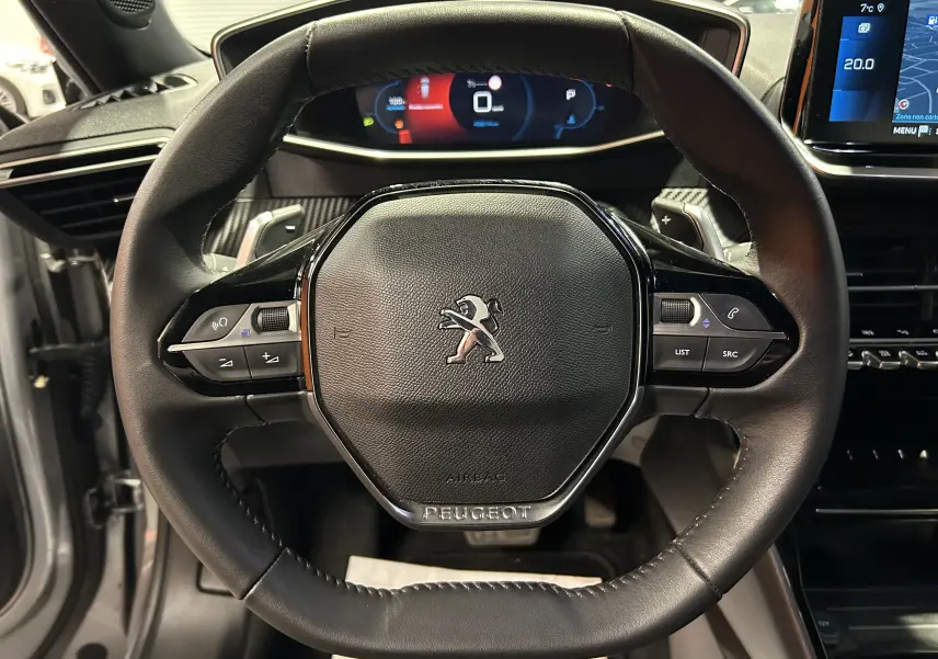 Vue rapprochée du volant en cuir noir du Peugeot 2008 gris Artense avec tableau de bord numérique et écran tactile GPS.
