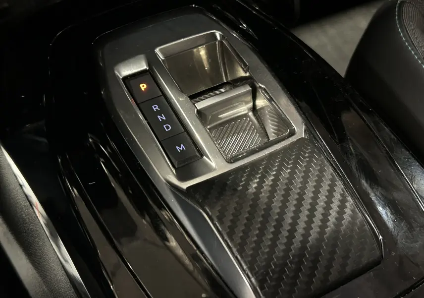 Gros plan sur la console centrale noire avec levier de vitesses automatique et finition effet carbone du Peugeot 2008 2023.