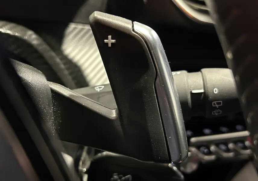 Gros plan sur la palette de changement de vitesse + au volant du Peugeot 2008 gris Artense, intérieur noir.
