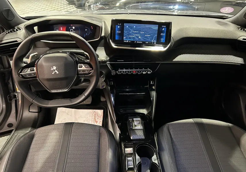 Vue intérieure avant du Peugeot 2008 gris Artense 2023, avec volant compact, écran GPS tactile et console centrale moderne.