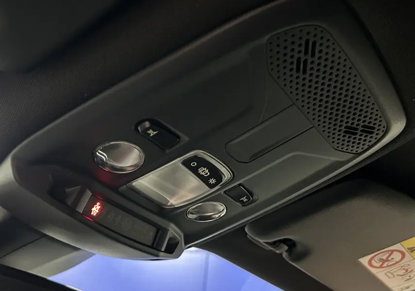 Plafonnier intérieur avec commandes d’éclairage et haut-parleur, vue en léger contre-plongée dans un Peugeot 2008 gris Artense.
