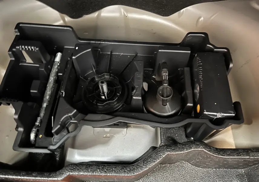 Rangement d’outils en plastique noir dans le coffre d’un Peugeot 2008 gris Artense, vue de dessus rapprochée.