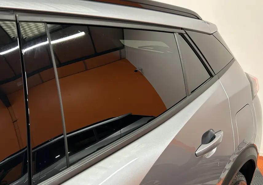 Vue latérale droite sur la partie arrière d’un Peugeot 2008 gris Artense avec vitres teintées et poignée de porte visible.