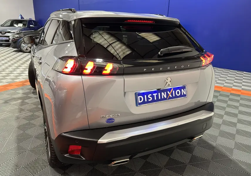 Vue 3/4 arrière droite du Peugeot 2008 gris Artense avec feux arrière allumés dans un showroom.