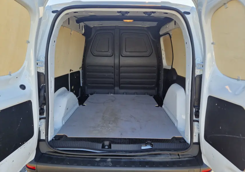 Vue arrière ouverte du Renault Kangoo blanc 2024, montrant l'espace de chargement vide avec parois en bois clair.