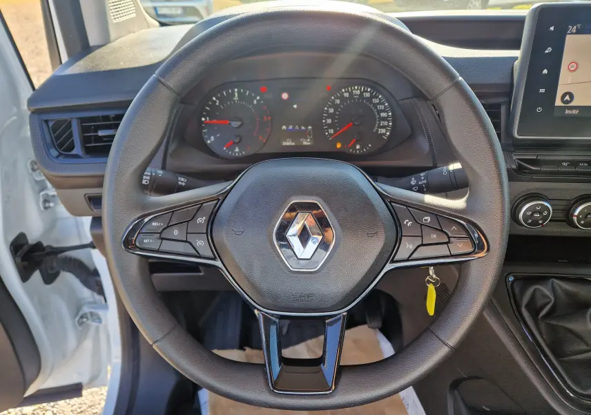 Vue intérieure centrée sur le volant noir du Renault Kangoo blanc 2024, avec tableau de bord et écran tactile visibles.