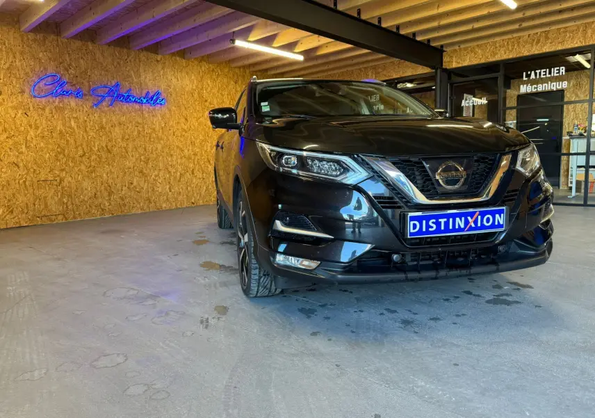 Nissan Qashqai noir vu de face en léger 3/4 avant droit, avec calandre chromée et jantes alu visibles.