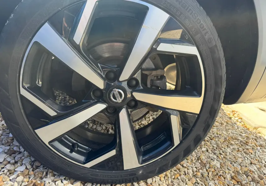 Gros plan sur la jante alu noire et argentée du Nissan Qashqai II PH2 2017, avec pneu RainSport 5 visible.