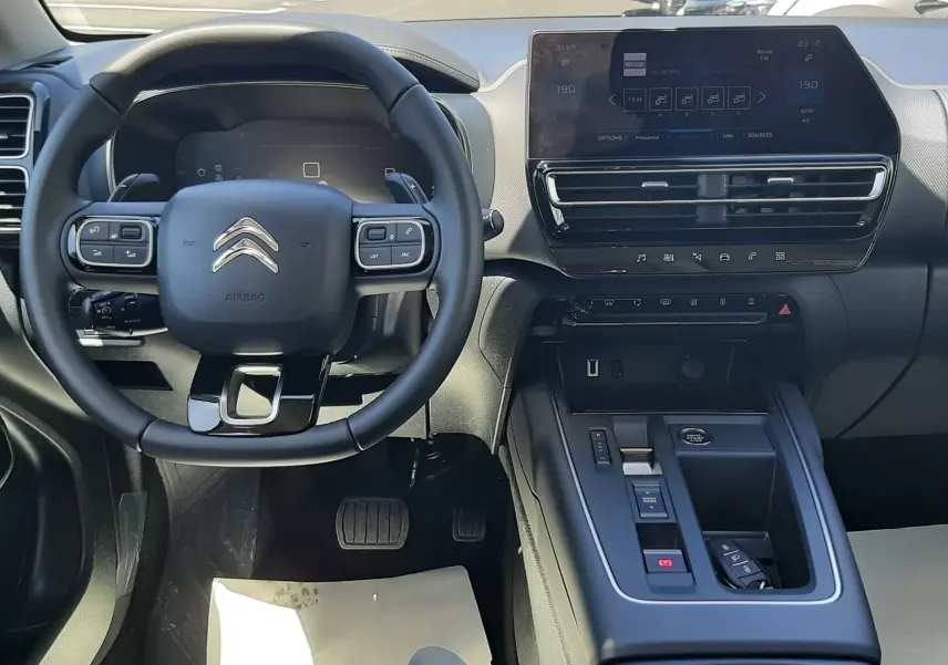 Vue intérieure du poste de conduite du Citroën C5 Aircross 2025, volant multifonction et écran tactile central en évidence.