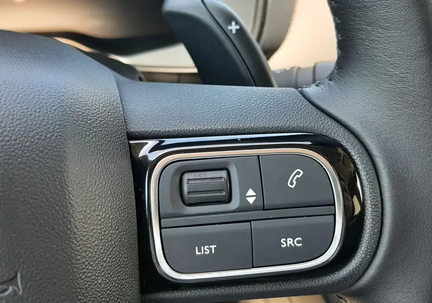 Gros plan sur les commandes multifonctions noires du volant cuir du Citroën C5 Aircross Ph.2 Hybrid 2025.