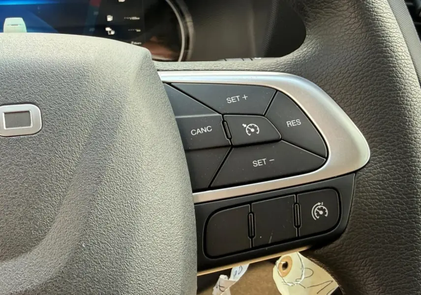 Gros plan sur le côté droit du volant noir de l'Iveco Daily 2.3 35S16 V12, avec commandes de régulateur de vitesse.