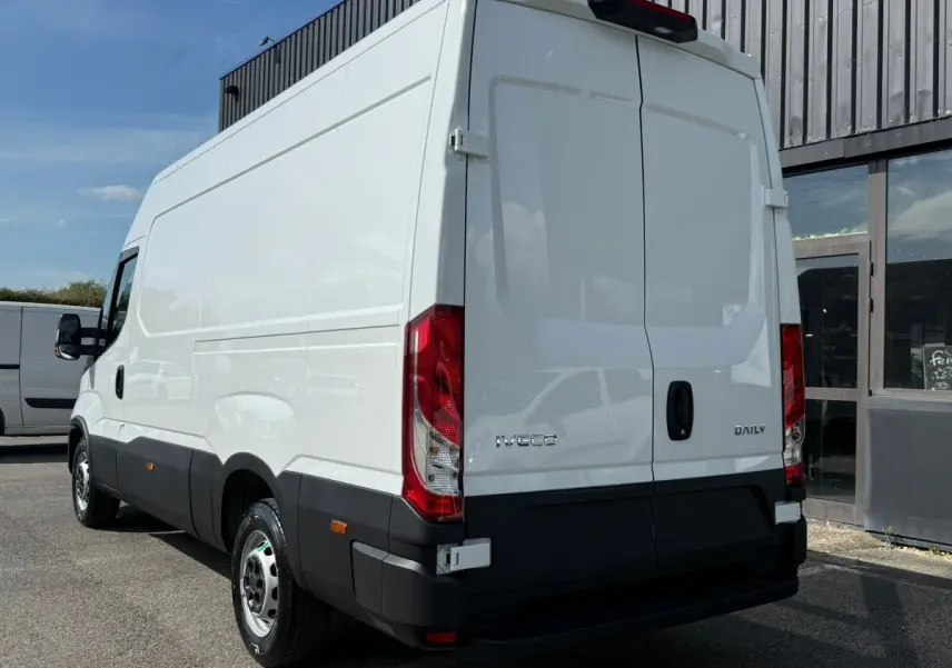 IVECO Daily blanc vu en 3/4 arrière droit, avec portes arrière fermées et feux rouges verticaux visibles.
