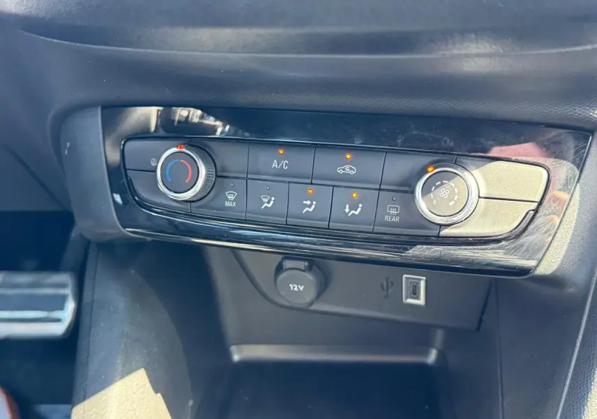 Gros plan sur la console centrale de l’Opel Corsa 2025, montrant les commandes de climatisation et les ports USB et 12V.