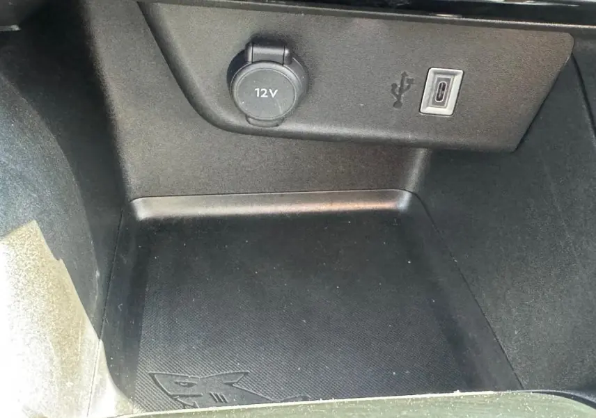 Gros plan sur la prise 12V et port USB-C dans le compartiment de rangement intérieur de l’Opel Corsa rouge 2025.