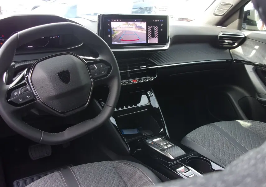 Intérieur moderne du Peugeot 2008 2024, vue côté conducteur, tableau de bord noir avec écran central affichant la caméra de recul.