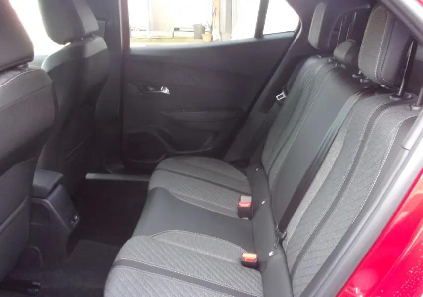 Vue côté droit de l'habitacle arrière du Peugeot 2008 rouge Elixir, montrant les sièges en tissu gris et noir.