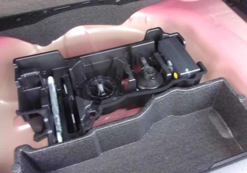 Gros plan sur le rangement à outils dans le coffre du Peugeot 2008 Rouge Elixir, version diesel 2024.