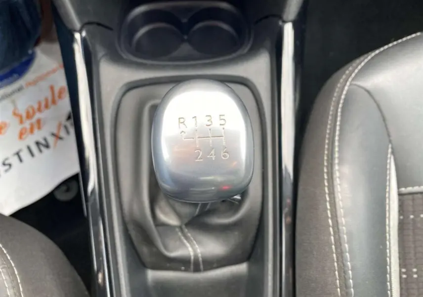 Gros plan sur le levier de vitesse manuel gris argenté du Peugeot 2008 2019, entouré de sièges noirs avec surpiqûres blanches.