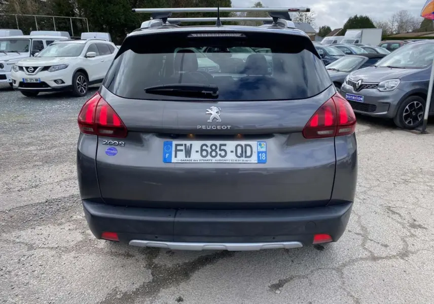 Vue arrière d’un Peugeot 2008 gris platinium 2019 avec barres de toit aluminium et caméra de recul visible.