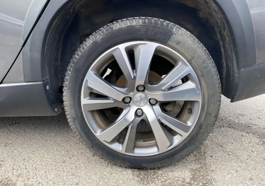 Gros plan sur la roue avant gauche du Peugeot 2008 gris platinium, mettant en valeur la jante alliage et le pneu.