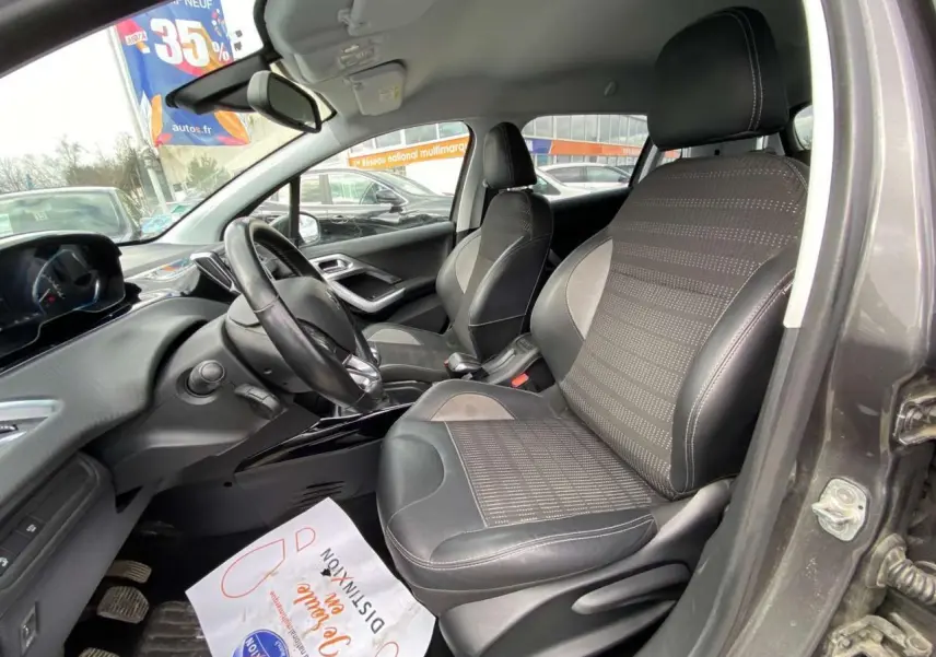 Intérieur avant droit du Peugeot 2008 gris platinium 2019, montrant les sièges en tissu et cuir et le tableau de bord moderne.