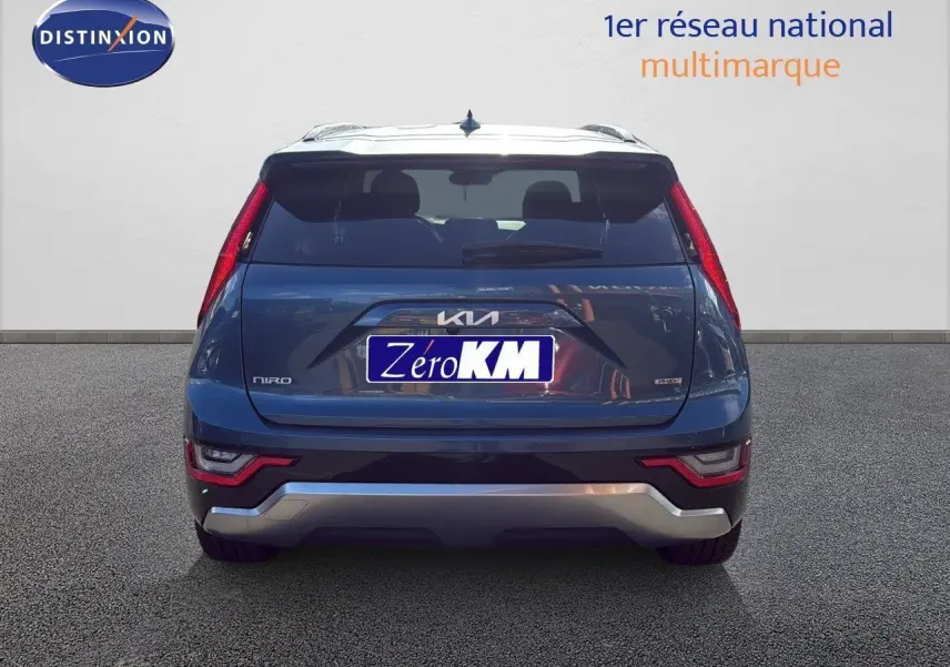 Vue arrière d'un Kia Niro bleu minéral metal 2025 avec feux arrière verticaux et logo distinctif sur le hayon.