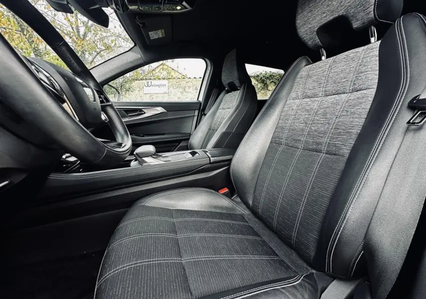 Intérieur de la Renault Austral 2024 vu côté conducteur, sièges tissu gris avec surpiqûres blanches et volant noir.