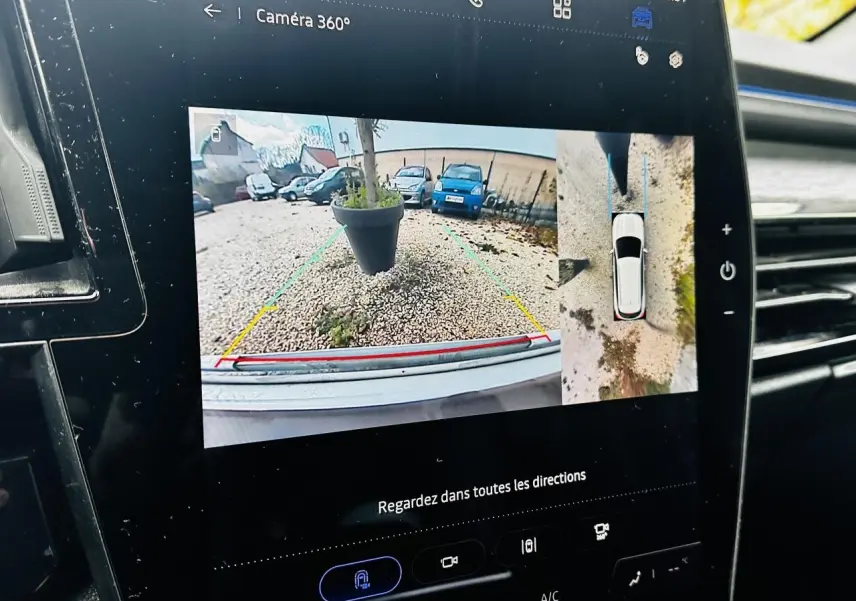 Écran tactile du Renault Austral blanc montrant la caméra 360° en vue arrière et vue aérienne du véhicule.