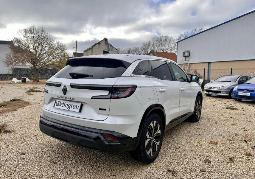 Renault Austral blanc en 3/4 arrière droit, avec feux LED et toit noir sur un parking extérieur.