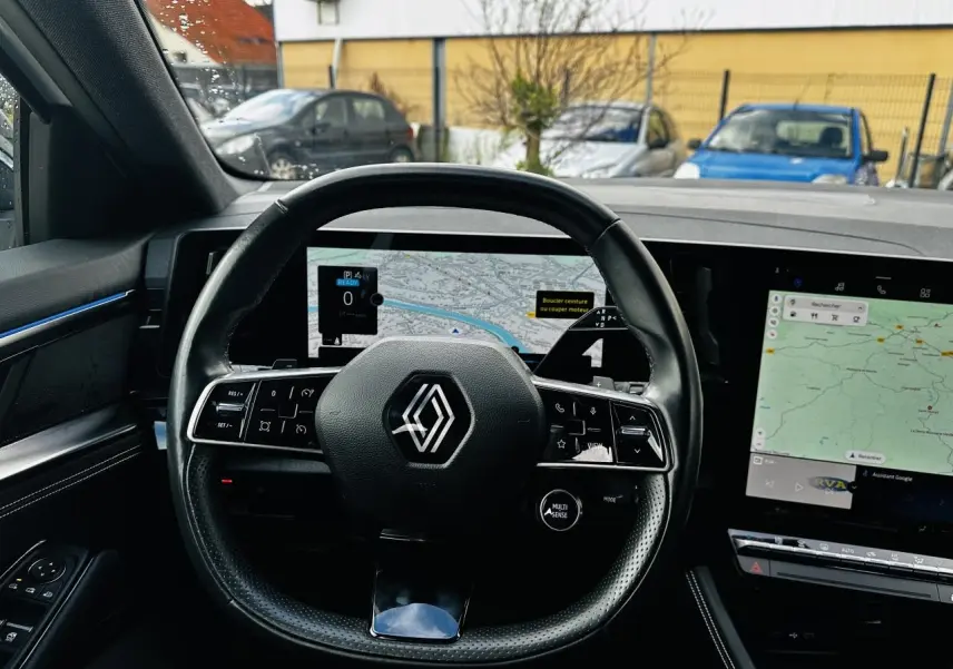 Vue intérieure centrée sur le volant noir de la Renault Austral 2024 avec tableau de bord numérique et écran tactile.