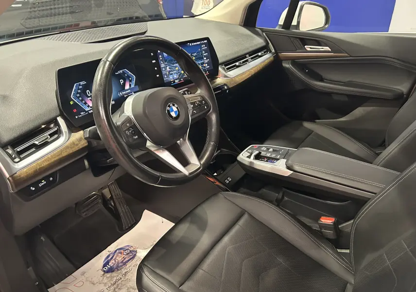 Vue intérieure côté conducteur de la BMW Série 2 Active Tourer 218i 2022 avec tableau de bord numérique et sellerie cuir noire.