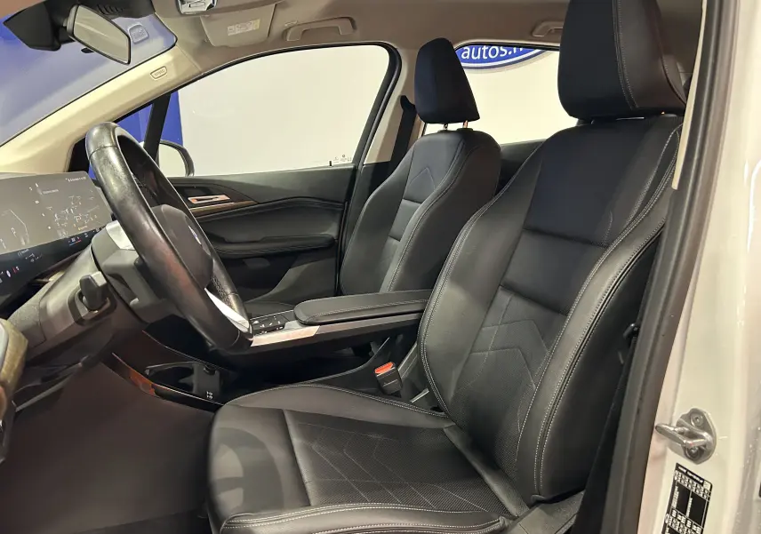 Vue intérieure côté conducteur de la BMW Série 2 Active Tourer blanche, sièges cuir noir et tableau de bord moderne.